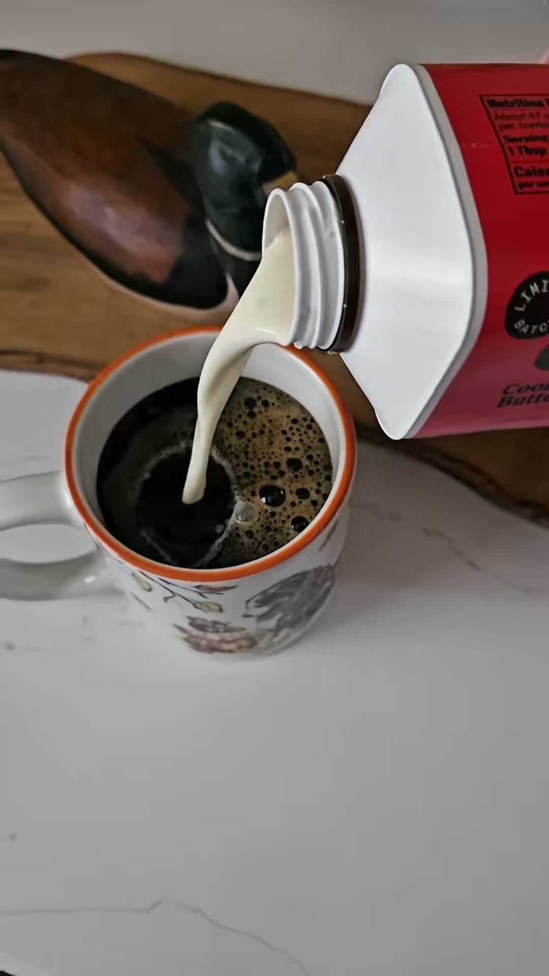 Cream pouring into a cup of coffee at home